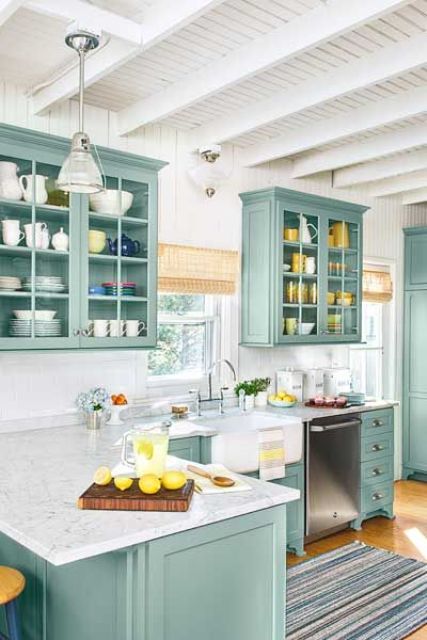 a beach turquoise kitchen with shaker and glass cabinets, wihte stone countertops, a white tile backsplash and touches of yellow for a fun look