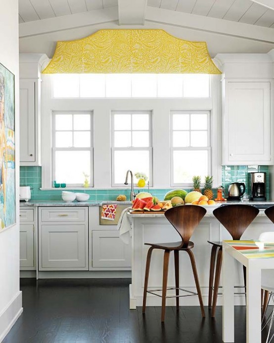 a tropical kitchen with white shaker style cabinets, a turquoise tile backsplash and a bold yellow blind plus colorful textiles