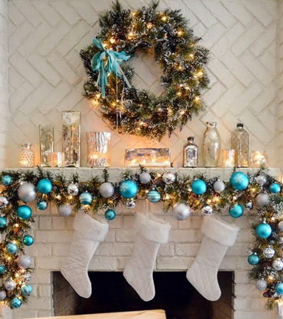an evergreen holiday garland with turquoise and silver ornaments, lights and stockings is a cool decoration for the holidays