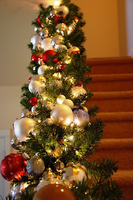 a catchy evergreen garland with lights and gold and red ornaments is a very chic and catchy decoration for Christmas