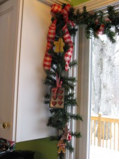 a holiday garland of evergreens, red plaid ribbon, gingerbread men, cookie forms and other kitchen stuff