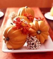 a white tray with faux pumpkins, bold blooms and waxwood blooms is a cool rustic centerpiece for the fall