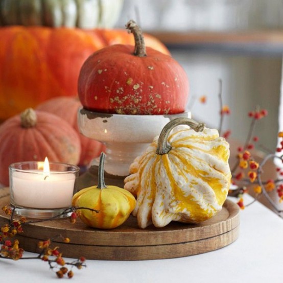 a wooden stand with a pumpkin and gourds, berries and a candle is a chic and cozy fall centerpiece to rock