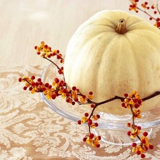 a glass plate with a white pumpkin and berry branches is a nice vintage inspired fall centerpiece idea