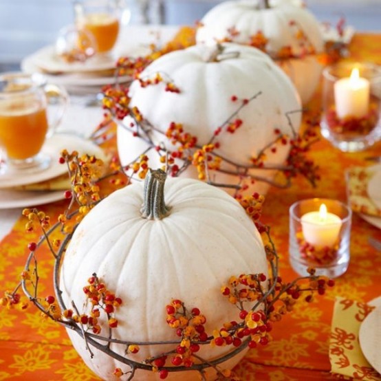 white pumpkins covered with branches with berries and candles in glasses make a cool wedding centerpiece with much texture