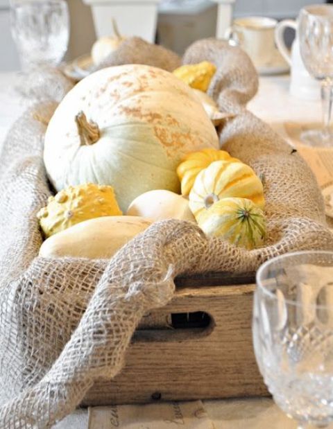 a crate with burlap, pumpkins and gourds is a rough rustic fall centerpiece for a fall tablescape