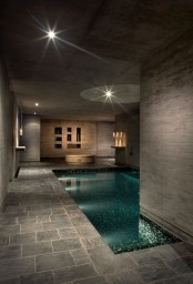 a stylish modern pavilion clad with stone tiles, with a large pool and some niches for storage, with furniture and shelves