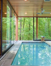 a contemporary pavilion with glazed walls and a large pool clad with stone tiles is a lovely space to be in and it’s a great place to enjoy forest views