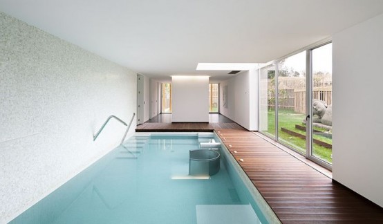 a minimalist pavilion with a large pool, a dark-stained deck, lights and a glazed wall to enjoy the views of the garden