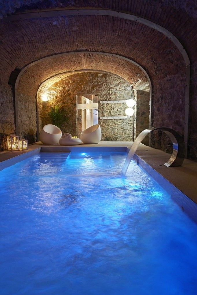 a home spa with an arched ceiling, a large blue pool with a faucet, some ultra modern white furniture