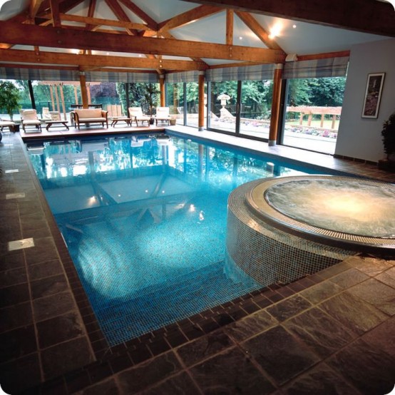 a large glazed pavilion done with stone tiles and wood, with a pool and a sitting zone is a lovely space to spend time