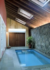 a small pavilion clad with tiles and natural stone, with a pool and some skylights to let natural light in