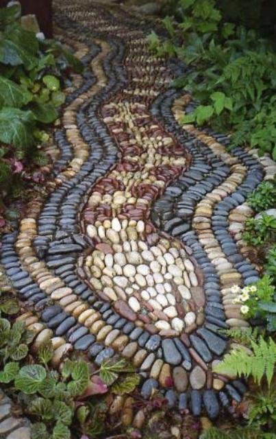 a pebble garden path that reminds a snake with burgundy, grey and neutral pebbles looks very unusual