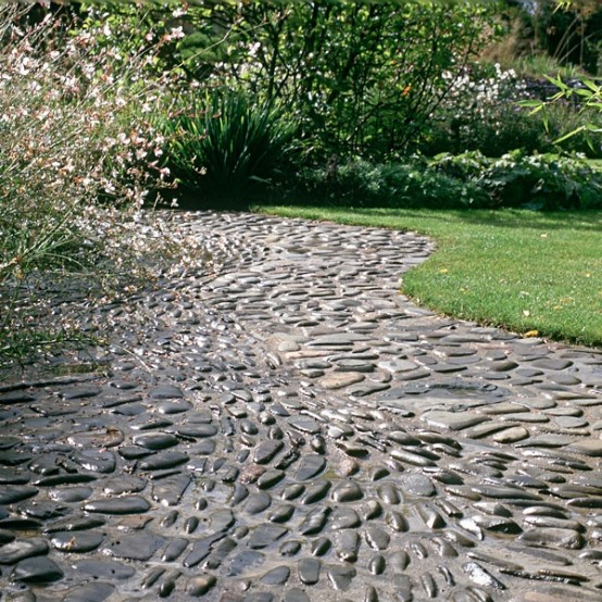 a black pebble garden path that contrasts the manicured lawn next to it and creates a bold and catchy look