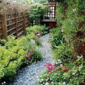 a small and tight pathway of grey pebbles with catchy and textural greenery next to it looks very cool and natural