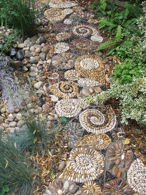 an earthy tone pebble path that imitates amonites is a great idea to go for next to a water feature like a pond here