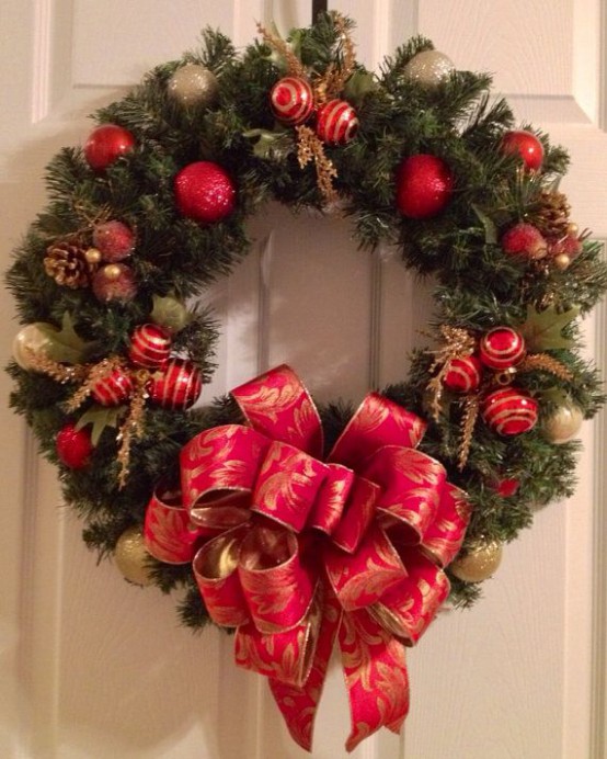 an evergreen Christmas tree of red and gold ornaments and ribbons, gilded pinecones and foliage