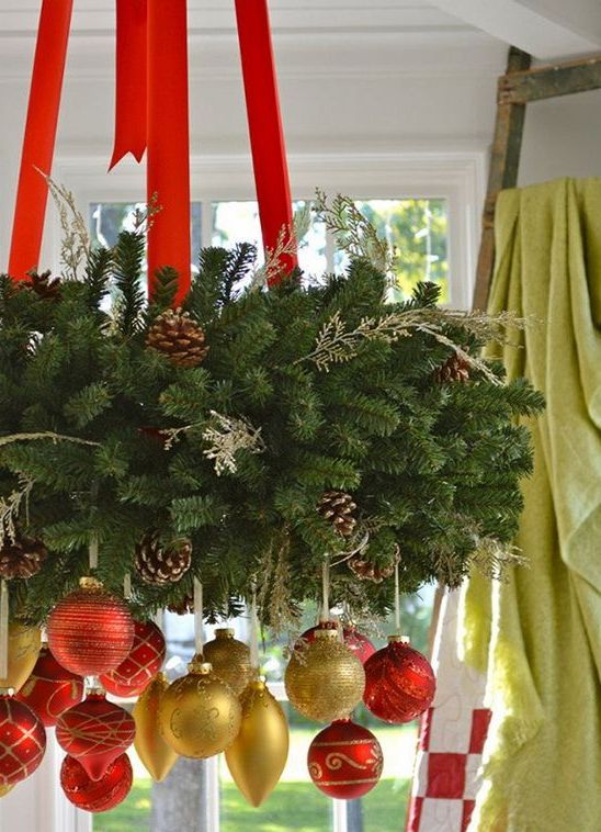 a gorgeous Christmas chandelier of evergreens, gold and red ornaments and red ribbons is amazing for holiday decor