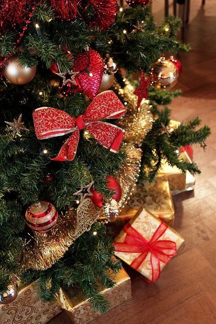 a Christmas tree gorgeously decorated in red and gold - with ribbons, bows and ornaments plus gift boxes