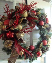 a lush evergreen Christmas wreath with gold and red glitter ornaments, bows and ribbons plus branches
