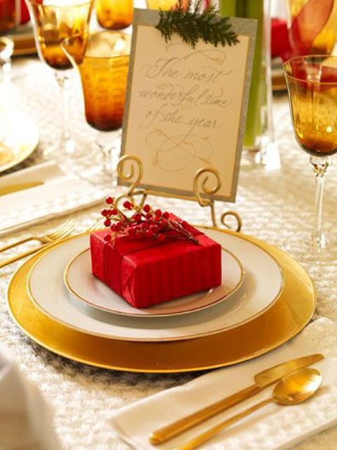 an elegant gold and red Christmas table with gold chargers and cutlery, amber glasses and evergreens