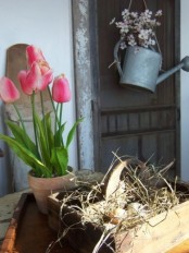 potted pink tulips, fake blooms in a watering can and a box with fake eggs for Easter