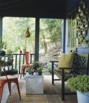 lots of potted flowers and some greenery plus bright pillows for a colorful spring porch