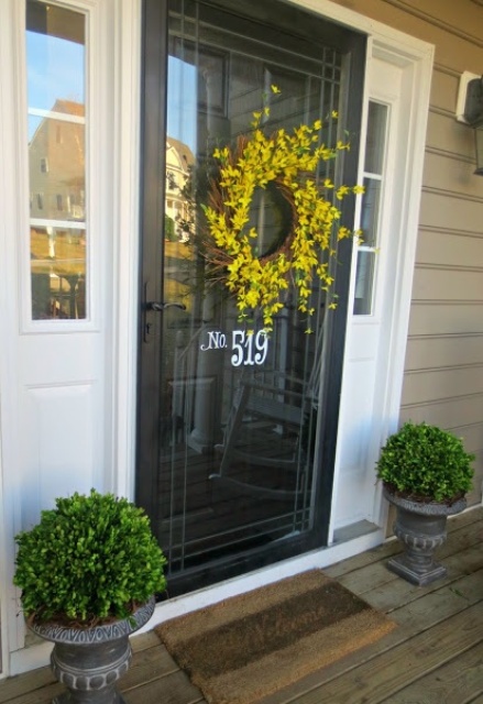 a couple of green topiaries in vintage urns and a bright yellow wreath on the door is a cool idea for spring