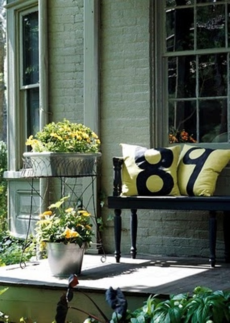 yellow blooms in buckets and bright yellow pillows on the bench to make the porch feel more spring-like