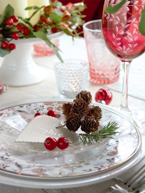 an elegant Christmas place setting with printed porcelain, red glasses and berries, pillar candles and colored candleholders