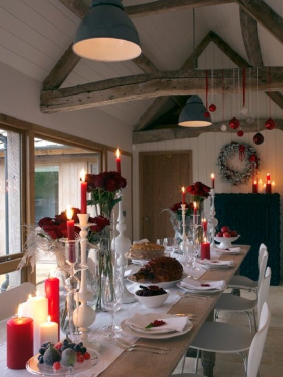 a bright Christmas tablescape with red roses and candles, white linens and fruits on the table