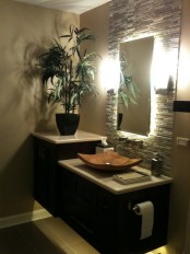 a tropical bathroom with neutral walls, a faux stone accent, a dark floating vanity and a wooden sink and potted plants