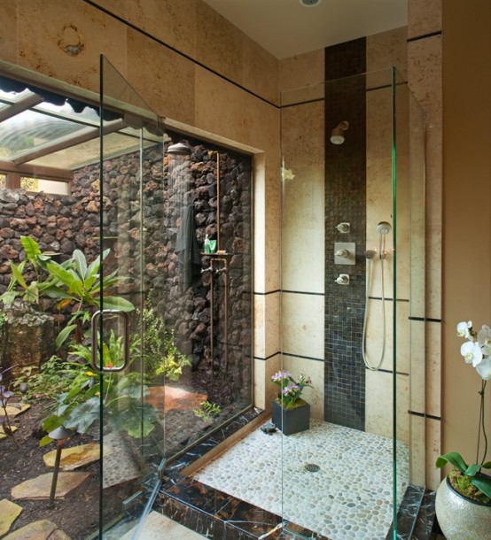 an indoor-outdoor bathroom with neutral walls, a glass enclosed shower with an entrance to an outdoor shower and tropical plants growing outdoors