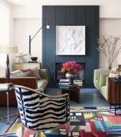a bright living room with a black faux fireplace, green seating furniture, a colorful color block rug and a zebra print chair for a more eye-catchy look