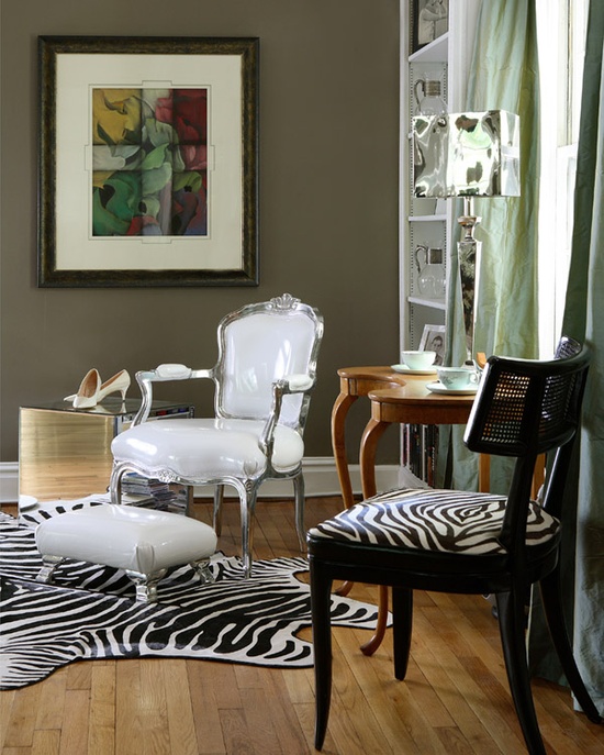 taupe walls, a vintage white chair and a zebra print one, a vintage table, a zebra print rug and a white footrest for a bold look