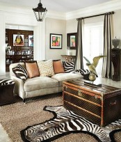 a bold living room with a grey sofa, zebra print pillows, a faux zebra rug, a dark chest for storage and some elegant black furniture pieces around