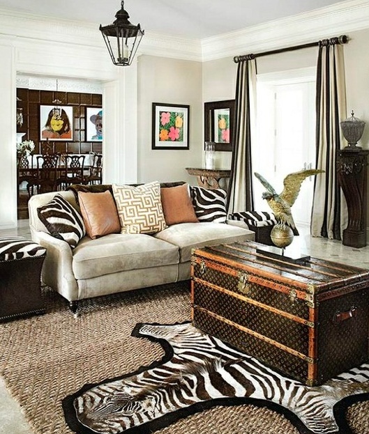 a bold living room with a grey sofa, zebra print pillows, a faux zebra rug, a dark chest for storage and some elegant black furniture pieces around