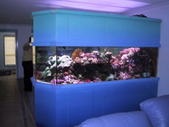 a large and long aquarium clad with panels works as a space divider between the living and dining room
