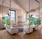 a stylish living room zone in neutrals limited on two sides by hanging aquariums that work as space dividers