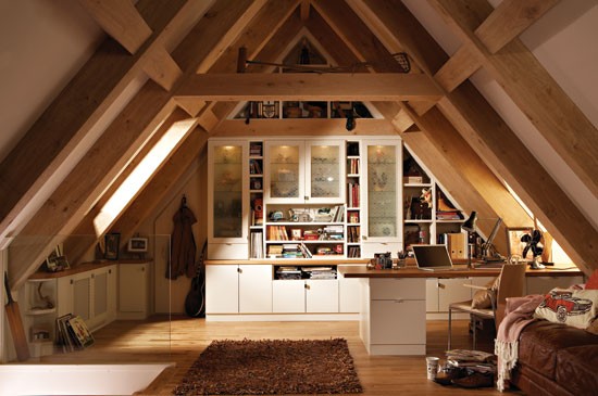 a welcoming contemporary home office with wooden beams on the ceiling, a large bookcase, lots of storage cabinets, a desk, a leather sofa and chair plus skylights for more natural light