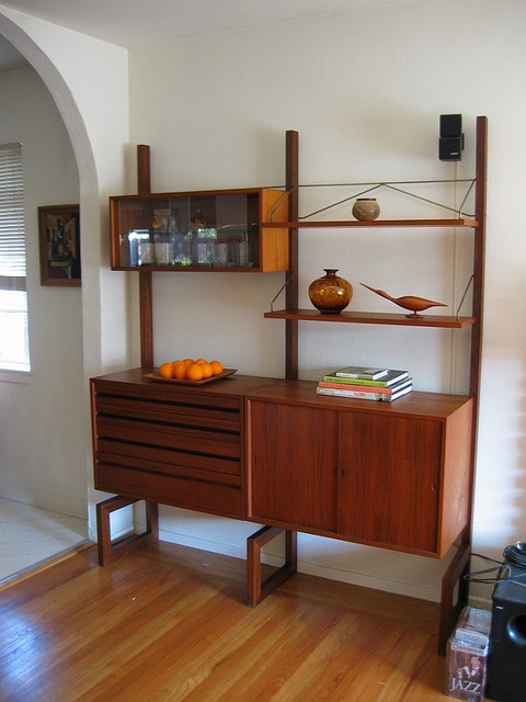 a rich stained storage unit with a closed storage compartment, drawers, open shelves and a box shelf with glass sliding doors