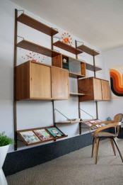 a large wall-mounted storage unit with closed cabinets, open shelves and slanted shelves looks lightweight yet will store a lot