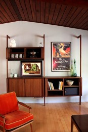 a mid-century modern wooden wall unit with open and closed compartments and artworks
