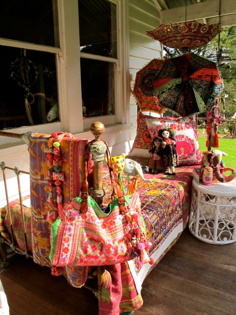 a boho porch with a sleeping nook - metal furniture with colorful printed textiles, bright umbrellas and a white table with toys