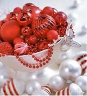 a silver bowl with red ornaments of various sizes and white ornaments around is a cool idea for festive table decor