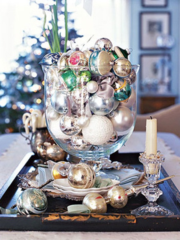 a tray and a glass bowl all filled with various colorful Christmas ornaments and candles for decor