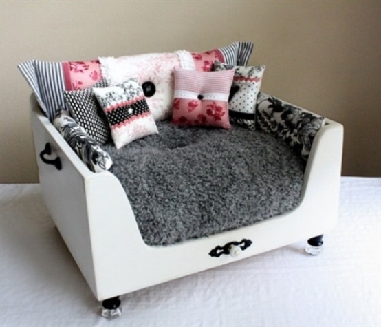 a small and cool dog bed made of a drawer with pretty glam legs, with a cozy fur cushion and lots of pillows