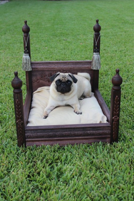 a refined dark-stained dog bed with pillars and tassels, with a neutral cushion is great for both indoors and outdoors