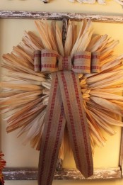 a large corn husk wreath decorated with a striped bow is a cool rustic outdoor decoration you can DIY