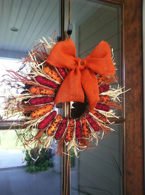 a bright rustic fall wreath made of corn cobs and corn husks and topped with an orange burlap bow with a button is a fantastic idea